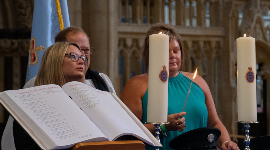 Photo of the Police Roll of Honour and candles being lit by family members in remembrance