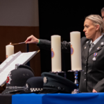 NPMD - officer lighting candle in memory of live lost in Wales