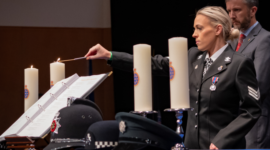 NPMD - officer lighting candle in memory of live lost in Wales